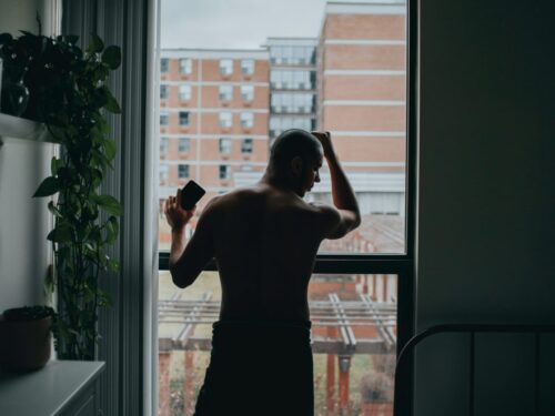man standing by the window beside bed